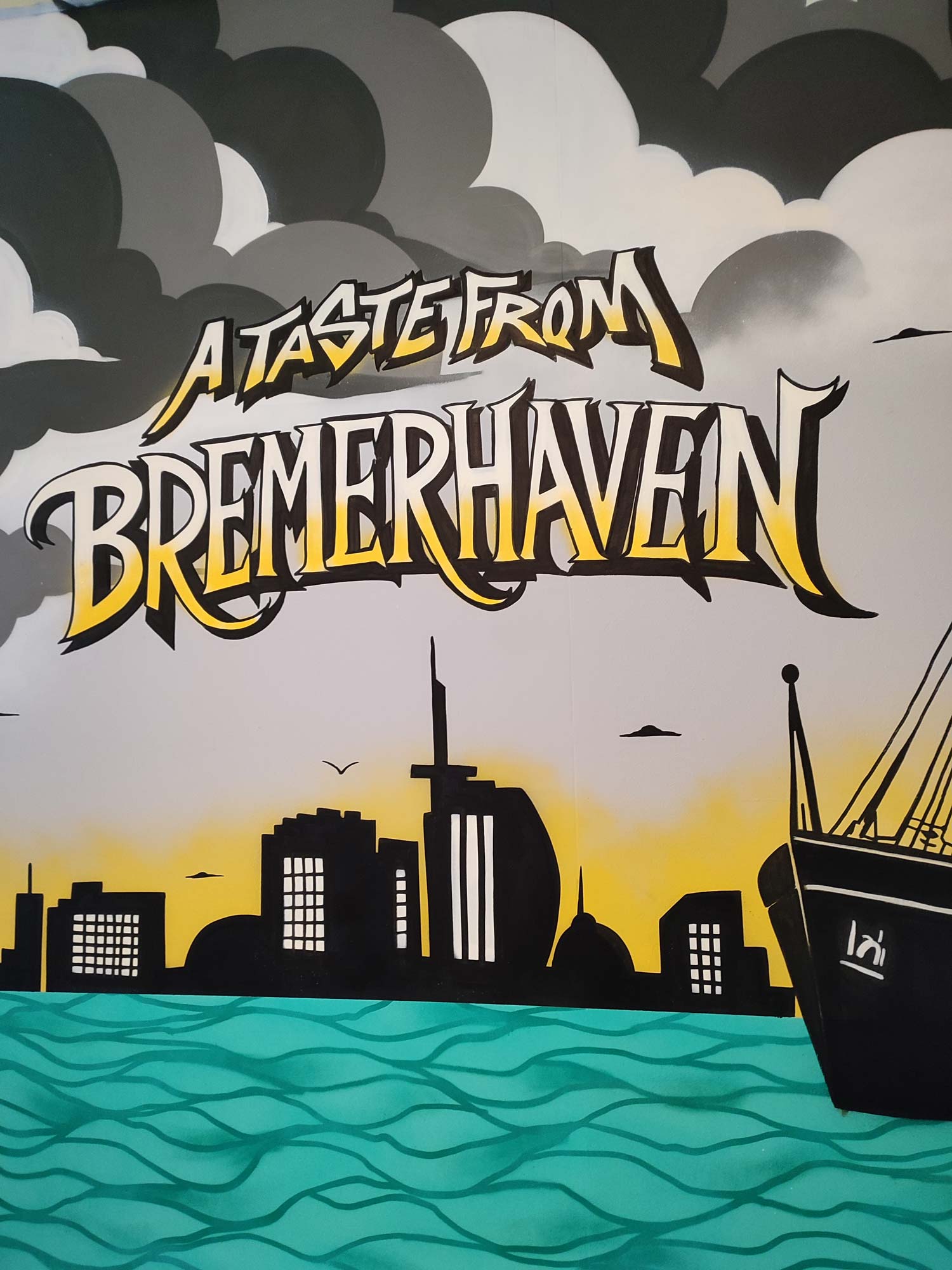 Buntes Auftragsgraffiti mit Schiffssilhouette und Skyline von Bremerhaven vor einem Sonnenuntergang und Wolken.