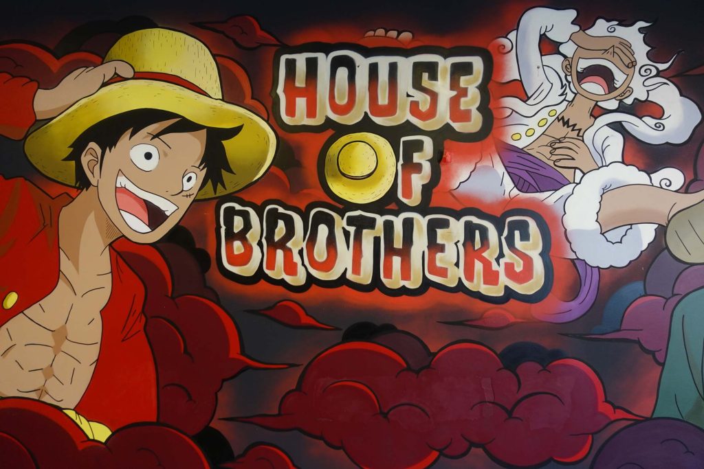 Auftrags-Graffiti im Fast-Food-Restaurant House of Brothers in Bremen, inspiriert von der Anime-Serie One Piece, mit lebhaften Charakteren und roten Wolken im Hintergrund.