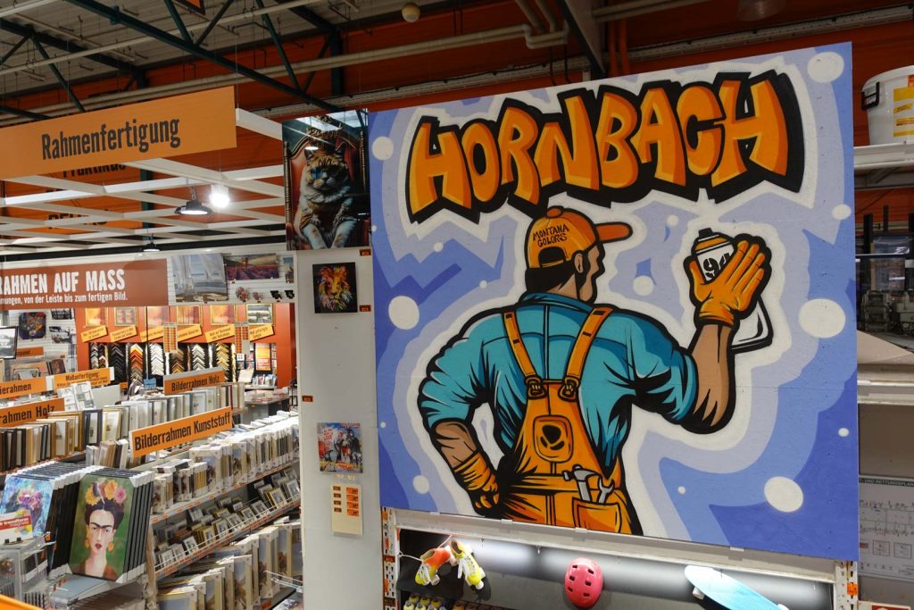 Graffiti-Kunstwerk im Baumarkt Hornbach mit einer stilisierten Figur, die eine Spraydose hält, und dem auffälligen Schriftzug 'Hornbach' in orangefarbener Comic-Optik.